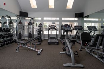 A gym with a variety of equipment including treadmills, weights, and exercise machines.